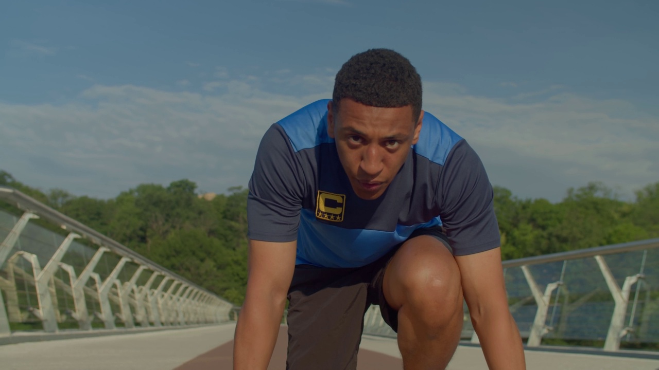 集中的黑人男性跑步者的肖像在开始位置准备比赛视频素材
