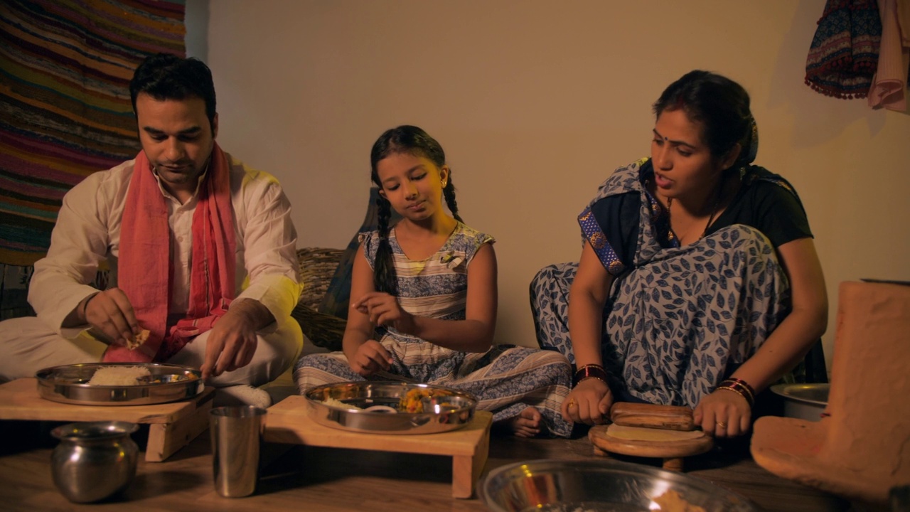 印度农村家庭主妇开心地给丈夫和女儿吃印度薄饼视频素材