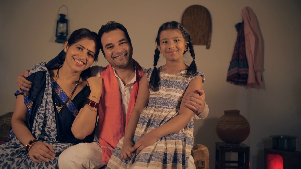印度父母开心地拥抱他们可爱的小女儿的乡村场景视频素材