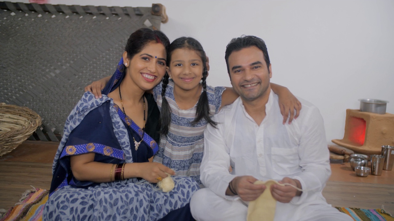 印度乡村的父母开心地拥抱他们可爱的女儿——养育，印度乡村的核心家庭，乡村父母视频素材