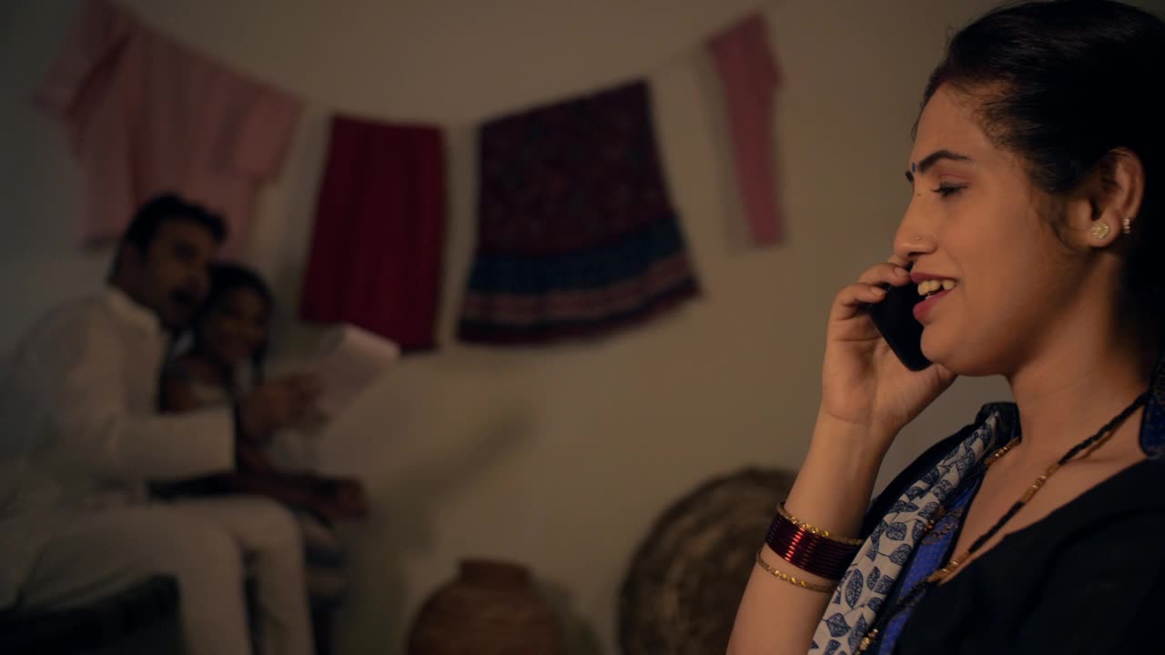 侧视图拍摄一个美丽的村庄妇女愉快地谈论电话-印度家庭在一个村庄，核心家庭视频素材