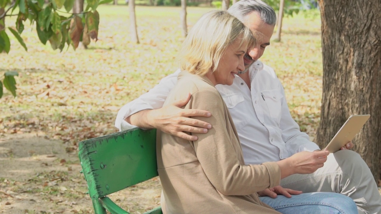 白种老年夫妇一起在公园的长椅上看书视频素材