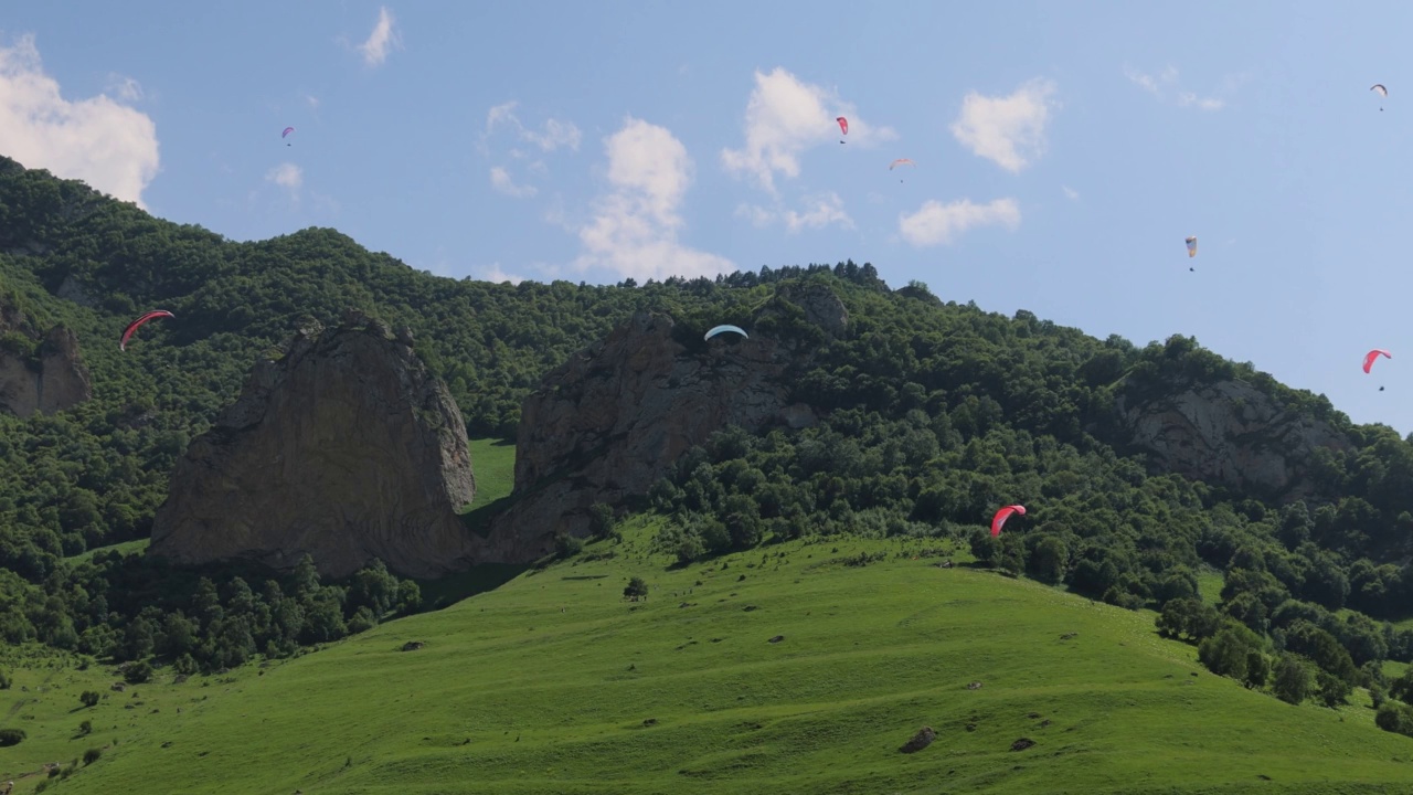 滑翔伞飞行员驾驶滑翔伞在云和青山之间飞行。视频素材