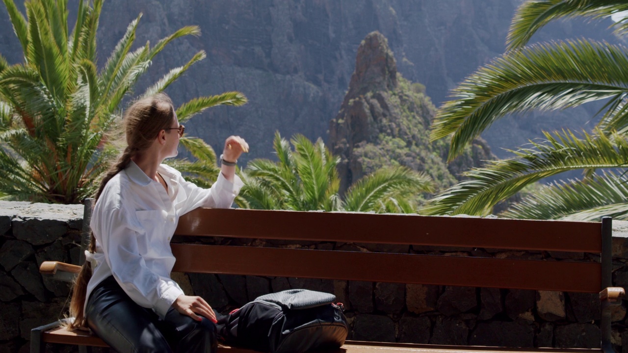 马斯卡峡谷和特内里费岛的村庄。美丽的年轻女子坐在长椅上欣赏风景视频素材
