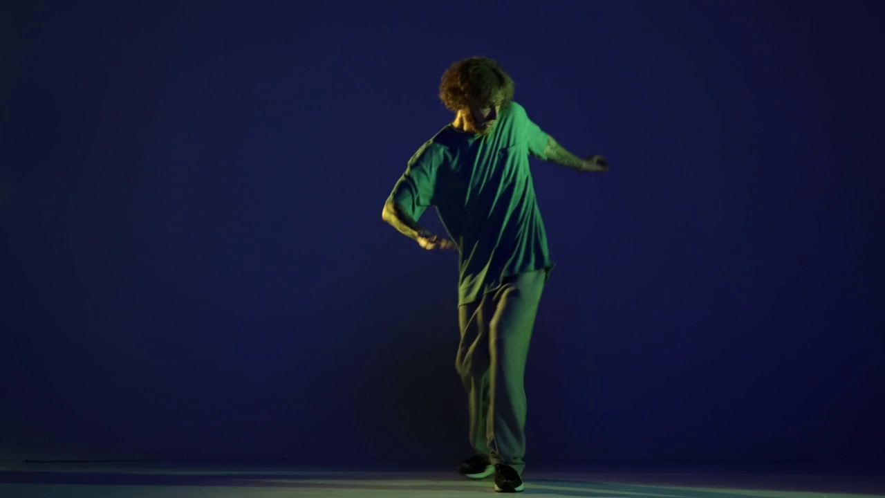 时髦的年轻人，嘻哈舞者在霓虹灯下的深蓝色背景上跳舞。现代舞艺术、时尚、青春、广告、风格。4 k、视频视频素材
