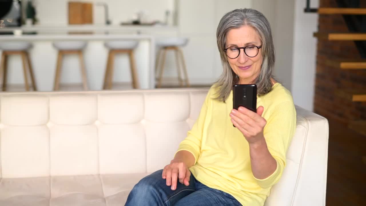 高兴成熟的灰色头发的女人女士通过视频连接在手机上在线交谈视频素材