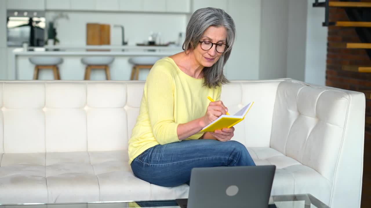 一位精力集中的退休妇女正在使用笔记本电脑在线学习视频素材