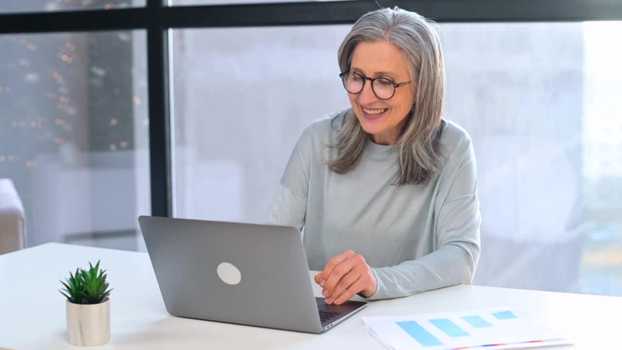 开朗微笑的头发花白的高级商务女性使用笔记本电脑进行虚拟通信视频素材