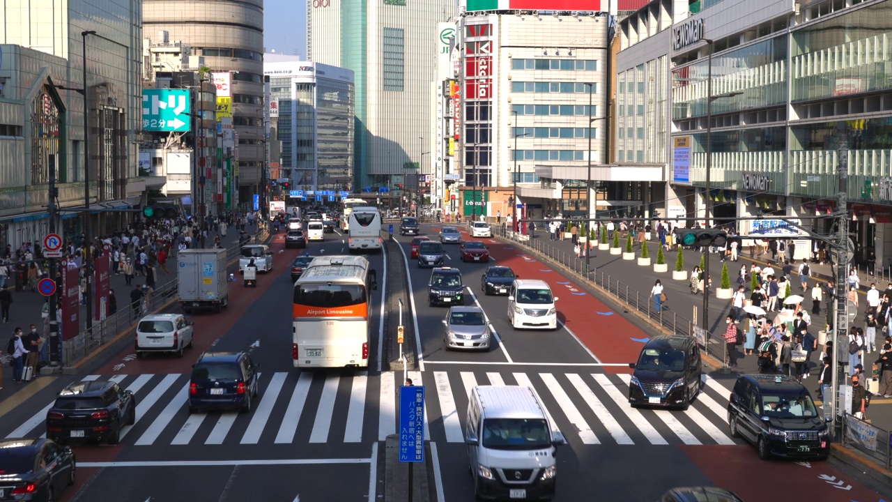 在日本东京新宿车站南出口的高楼大厦之间，车辆穿梭于海道-九州大道视频素材