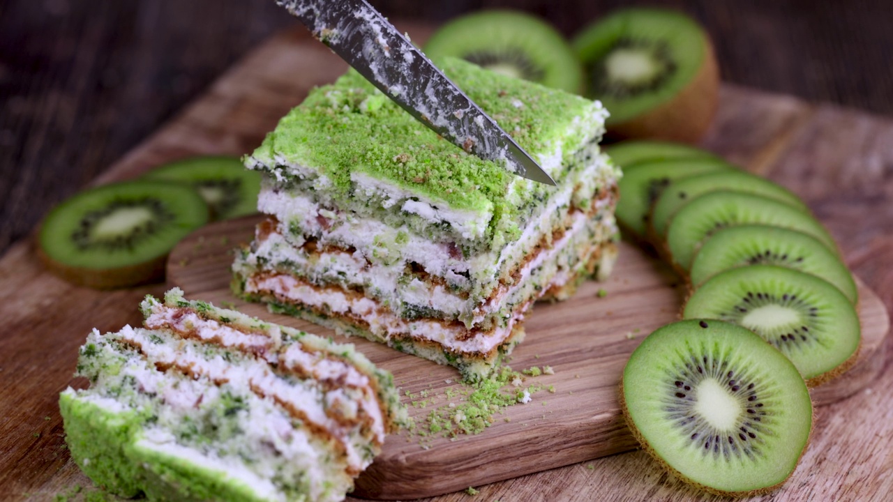切一个水果口味的绿色蛋糕和绿色猕猴桃片视频素材