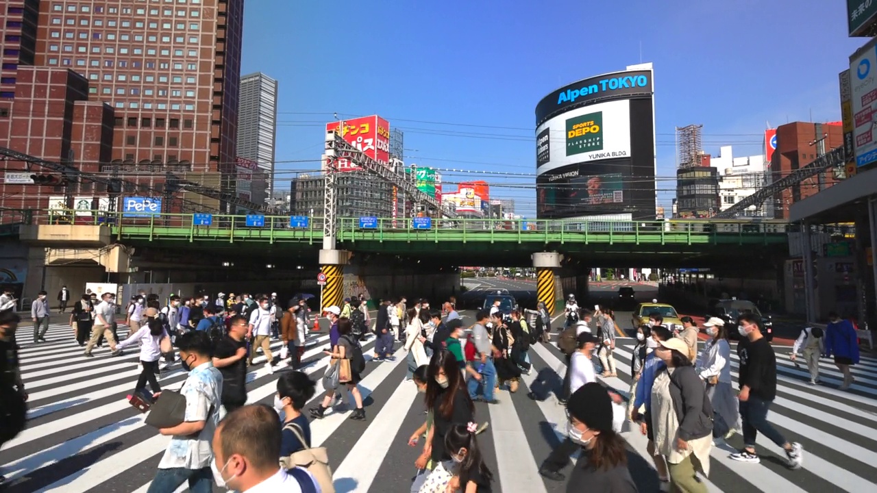 在日本东京新宿车站西出口附近，人群穿过长长的人行横道视频素材
