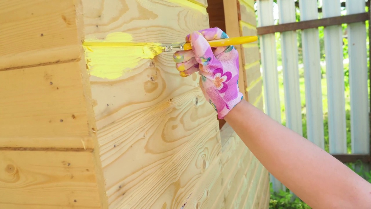 一个女孩用刷子刷一堵黄色的墙，视频素材
