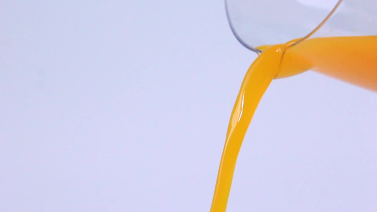 将橙汁倒入白色底色的玻璃杯中视频下载