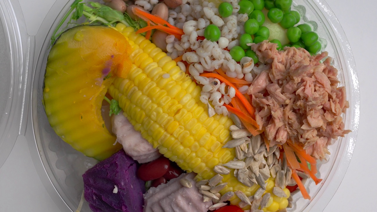 混合新鲜沙拉在一次性塑料盒旋转白色背景。视频下载