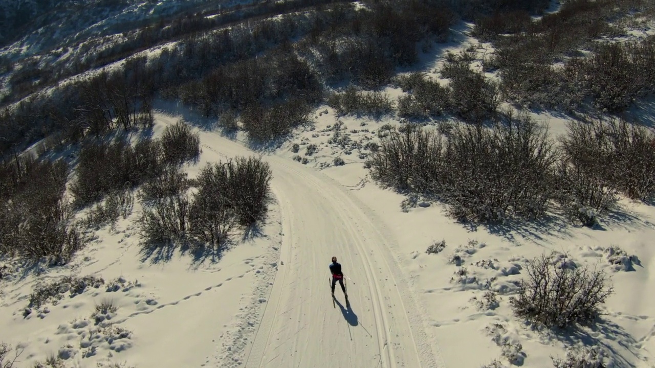 空中向前拍摄的女人与滑雪杆走在雪山度假-士兵空心，犹他州视频下载