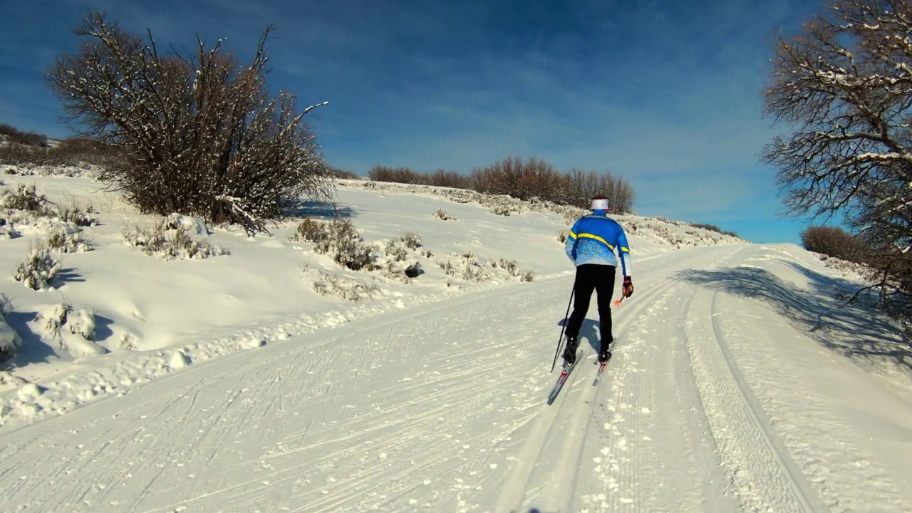在阳光明媚的日子里，带着滑雪板在雪地上奔跑的人的平移镜头-士兵山谷，犹他州视频下载