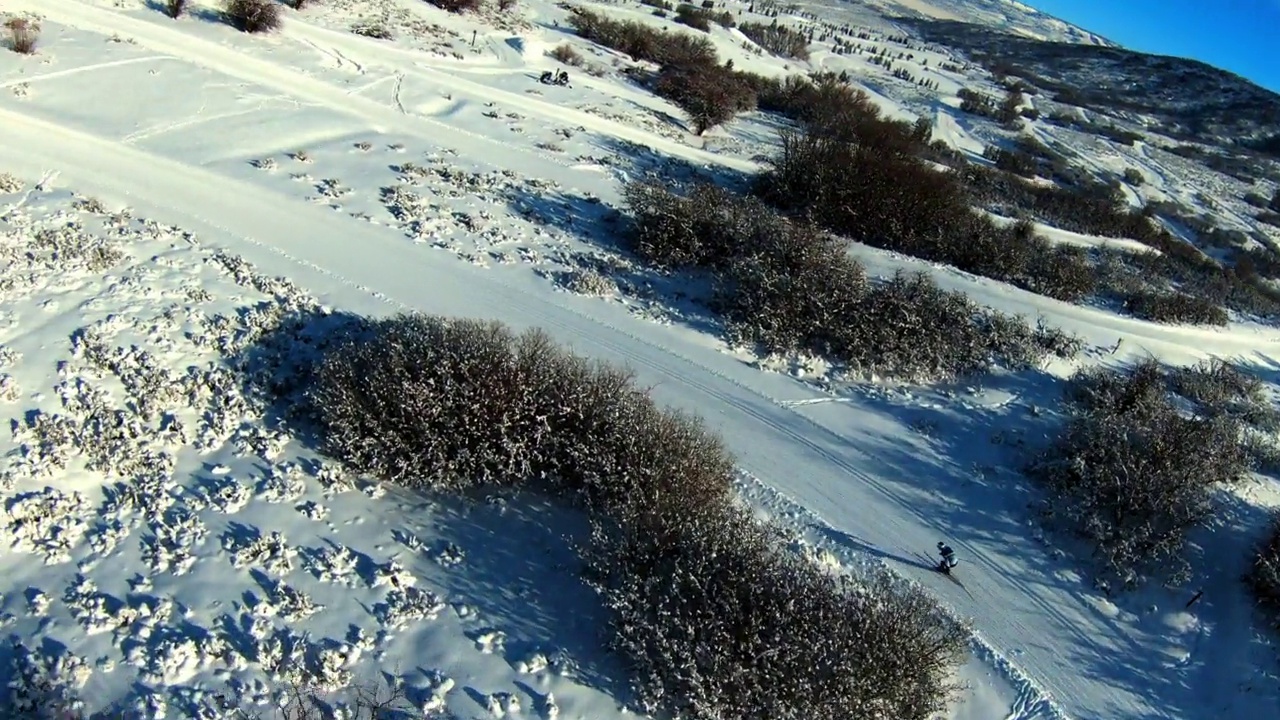 空中平移拍摄的男性游客在山上滑雪，无人机向前飞行在雪域景观-士兵空心，犹他州视频下载