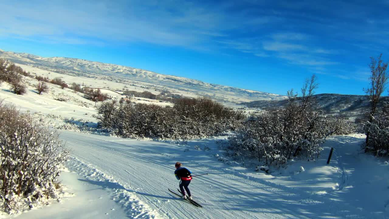 空中向前拍摄的女性游客滑雪雪景在阳光明媚的日子-士兵空心，犹他州视频下载