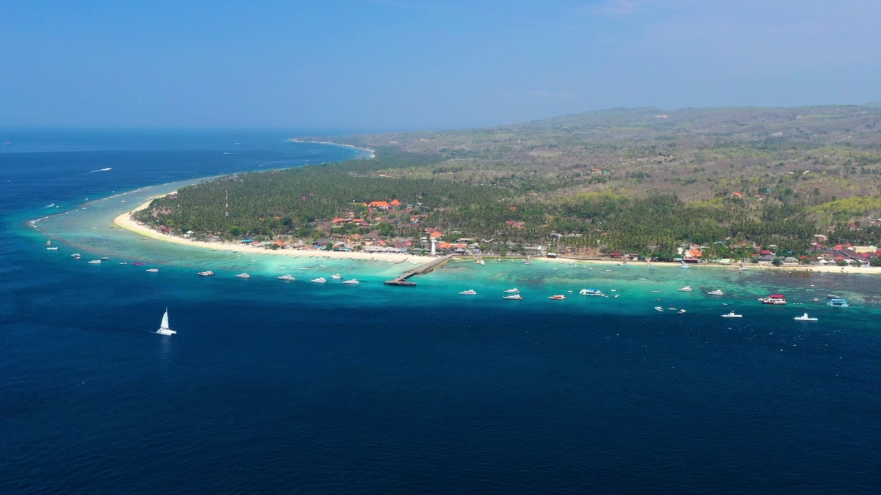 航拍在深蓝色的热带海岸线和遥远的海港上空——印尼巴厘岛视频素材
