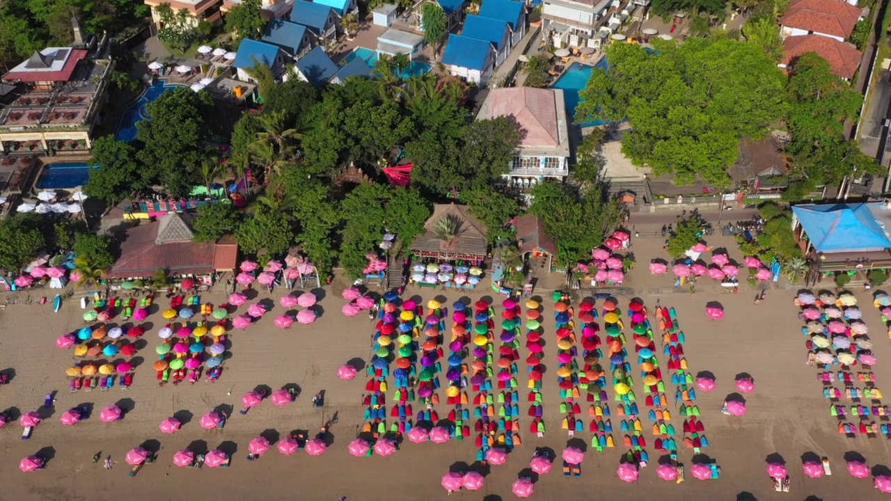 带着色彩鲜艳的伞，在拥挤的热带巴厘岛海滩上空中倾斜——印尼库塔视频素材