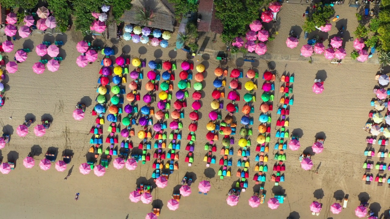 带着色彩鲜艳的伞在拥挤的热带巴厘岛海滩上空空中旋转——印尼库塔视频素材