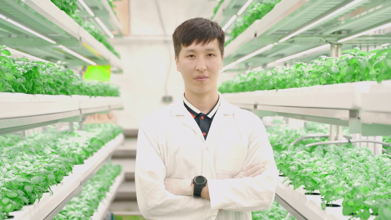 在科技城农场的温室里，年轻的亚洲男人的肖像视频素材