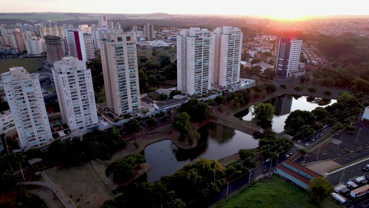 无人机拍摄于Ribeirão Preto SP巴西城市Parque das Artes顶部的画面。公园有一个美丽的湖，周围有一些建筑。傍晚时分，在一个美丽的、保存完好的城市和大都市，夕阳西下。视频素材