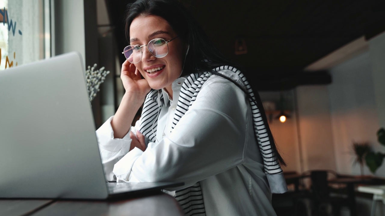 微笑的女人在咖啡馆用笔记本电脑视频通话视频素材