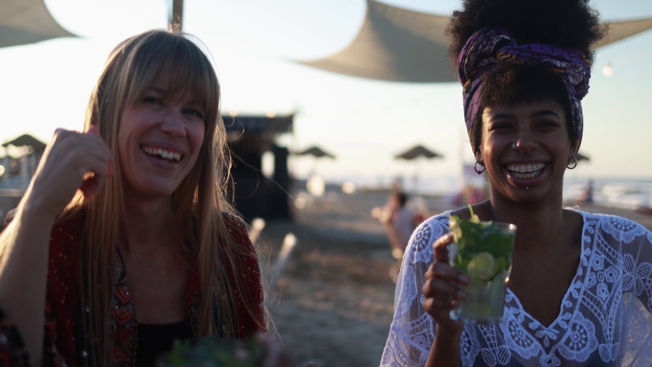 年轻的多种族女性在夕阳背景下的海滩派对上喝着莫吉托鸡尾酒视频素材