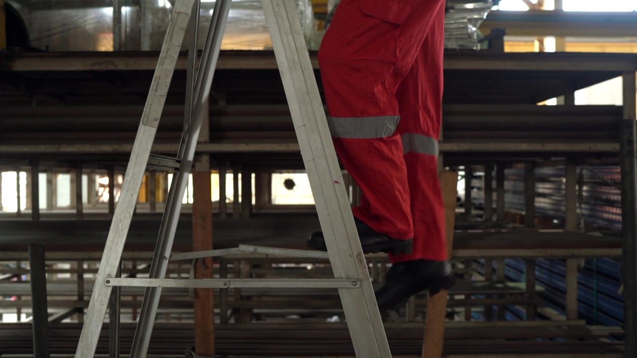 工作安全-近距离拍摄的一个工人的腿安全下降的梯子视频素材