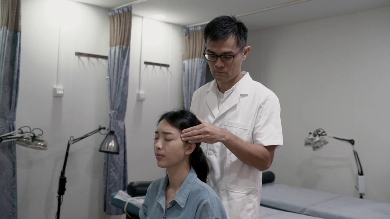 中医疗法——中医按摩病人的太阳穴以治头痛视频素材