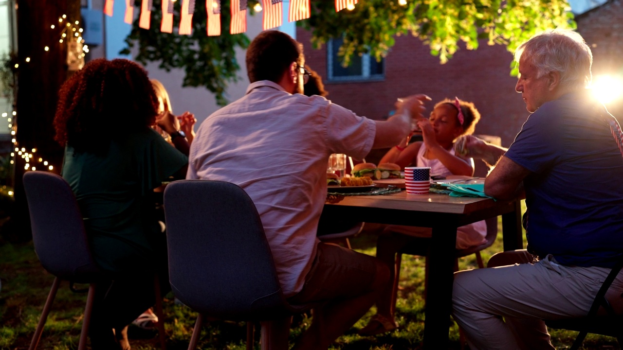 快乐的多民族家庭在花园晚宴上吃汉堡视频素材