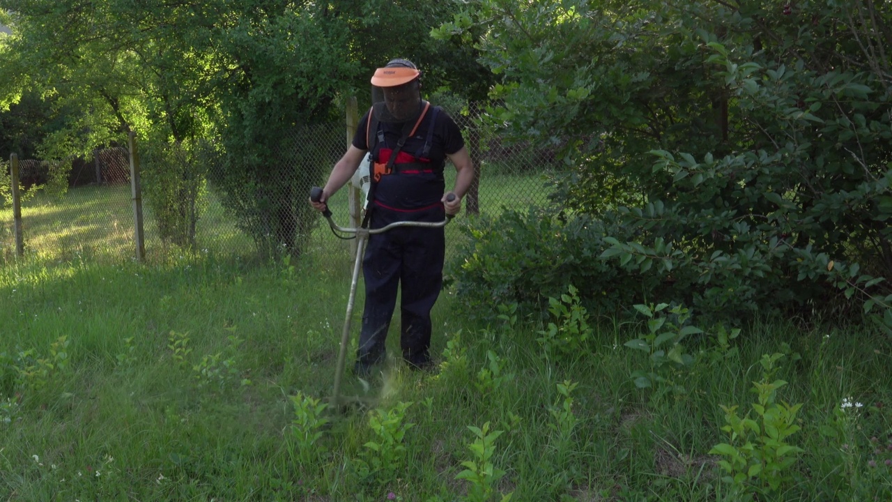 年轻人在后院用割草机修剪非耕作的草视频下载