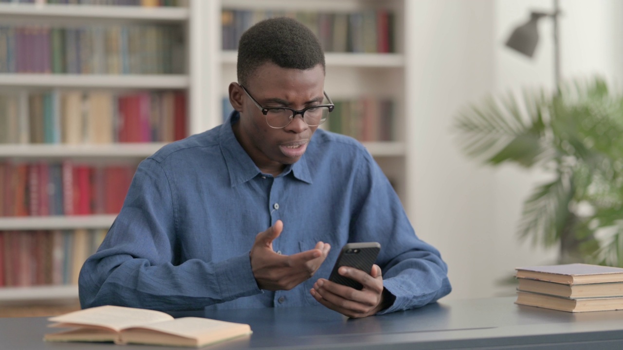 沮丧的非洲年轻人对智能手机上的损失做出反应视频素材