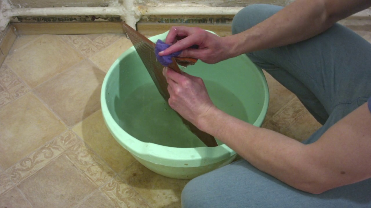 年轻的男性清洁工在家里用碗清洗旧瓷砖。视频素材