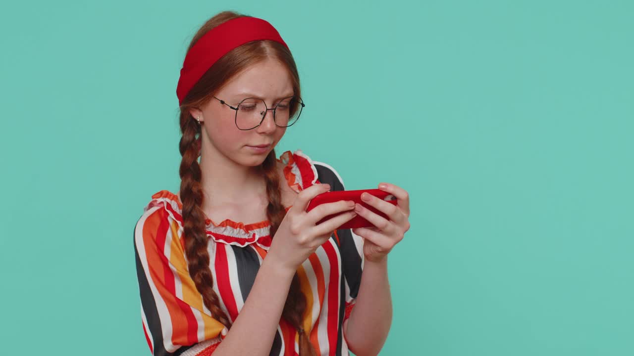 担心有趣的红发女孩热情地玩赛车视频游戏在手机上视频素材