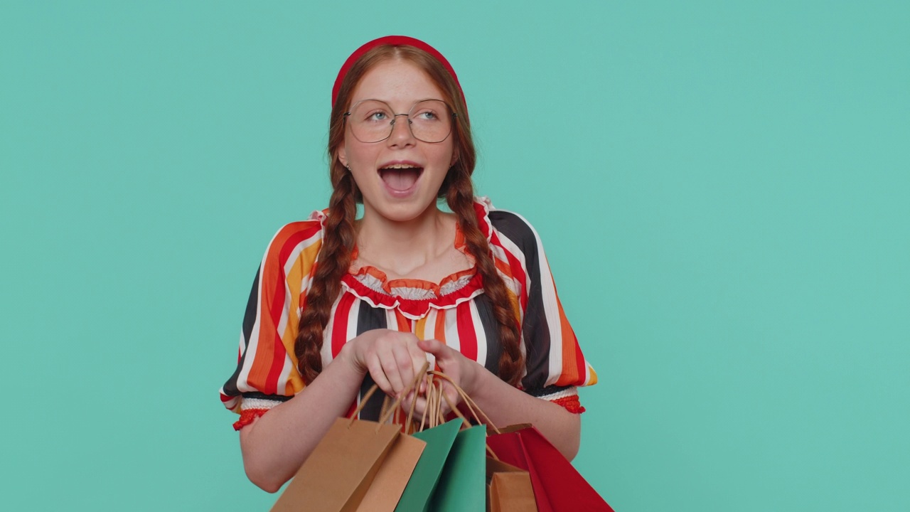 红发女孩展示购物袋，广告折扣，微笑着对低价感到惊讶视频素材