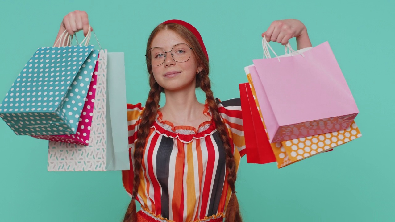 姜姑娘展示购物袋，广告打折，微笑着看起来对低廉的价格感到惊讶视频素材