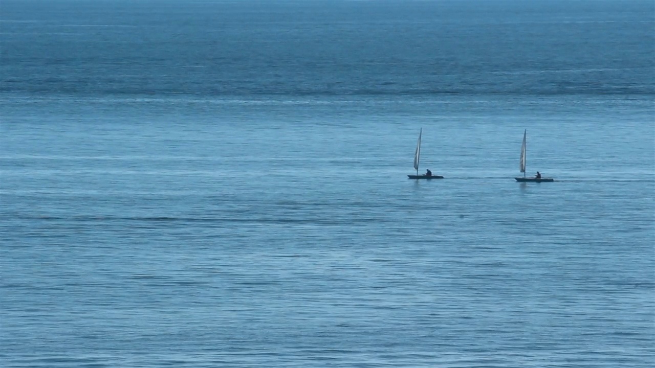 两艘独木舟在平坦的蓝色大海上划行。视频下载