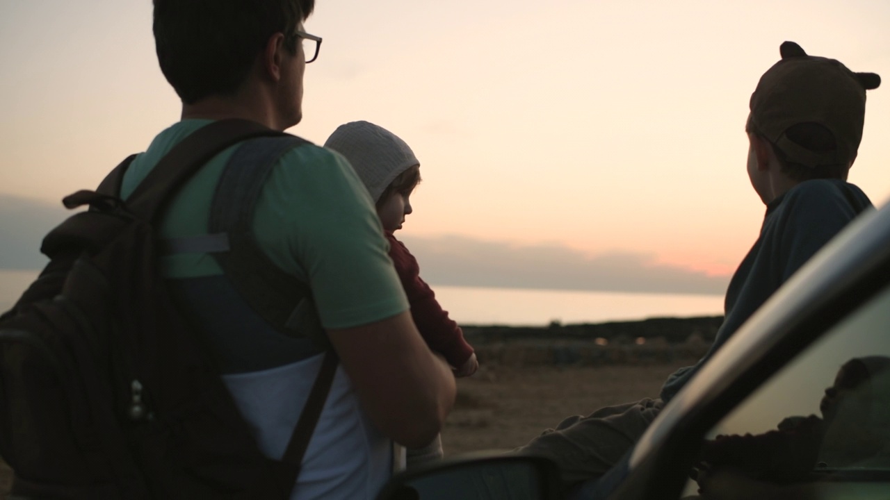 男人带着儿子和女儿在海滩上享受日落视频素材