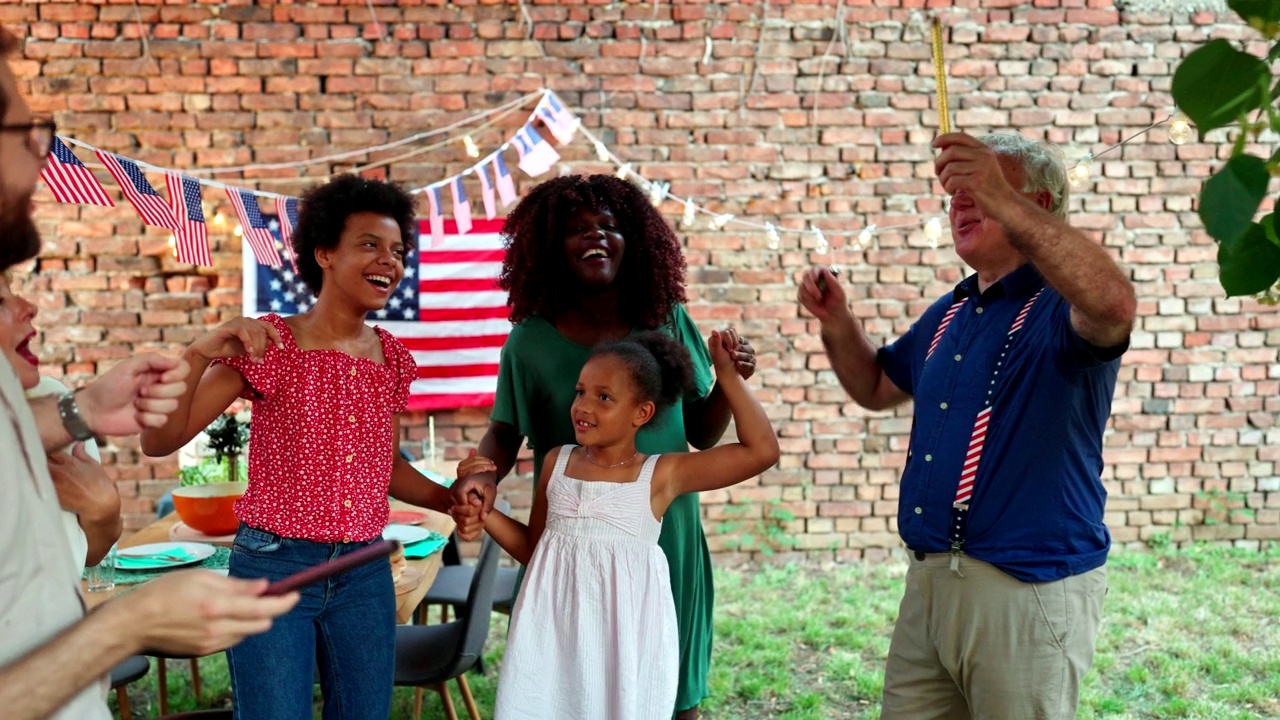 快乐的多民族家庭庆祝户外7月4日在后院聚会的烟火视频素材