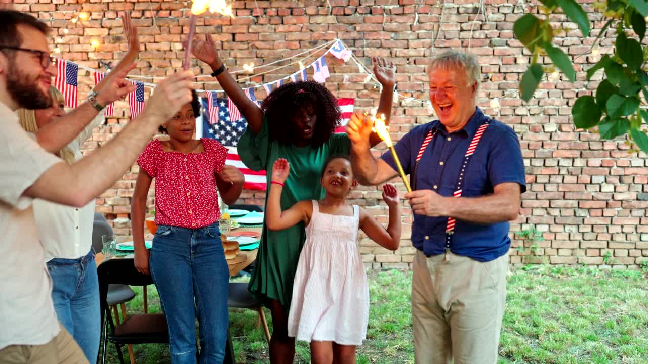 快乐的多民族家庭庆祝户外7月4日在后院聚会的烟火视频素材