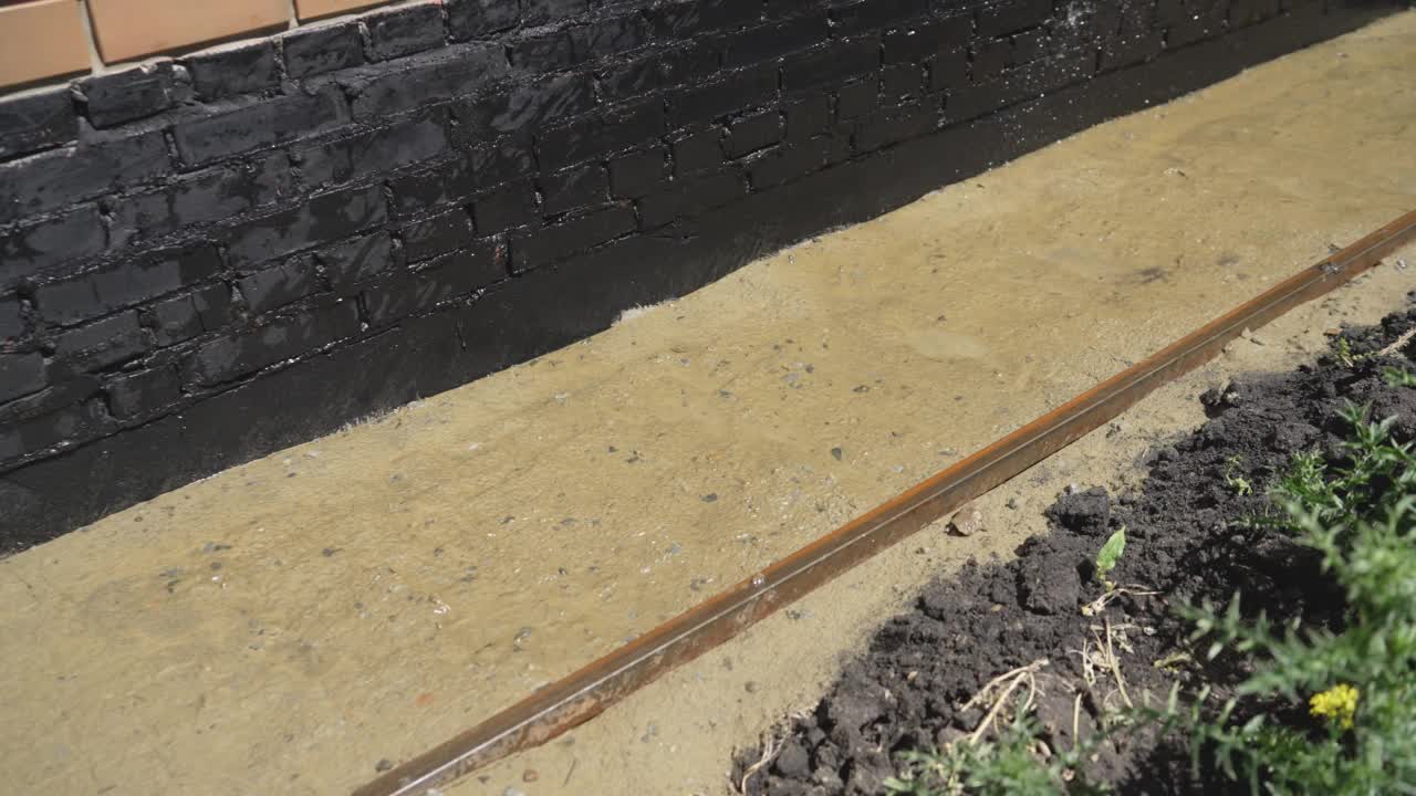 用沙子灌水铺设铺路板。铺设铺路板的过程。铺路板用砂石加湿。沙子从软管中倒出来。视频下载