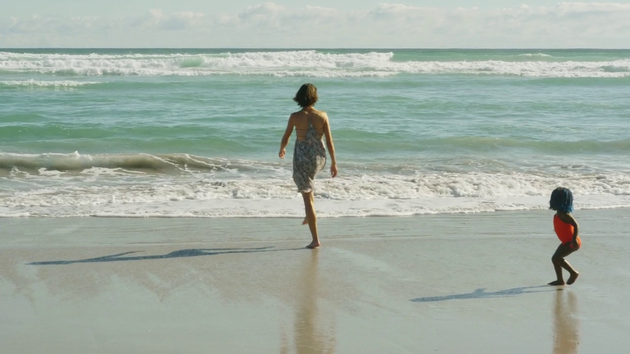 快乐的母女在阳光明媚的海滩上奔跑玩耍视频素材