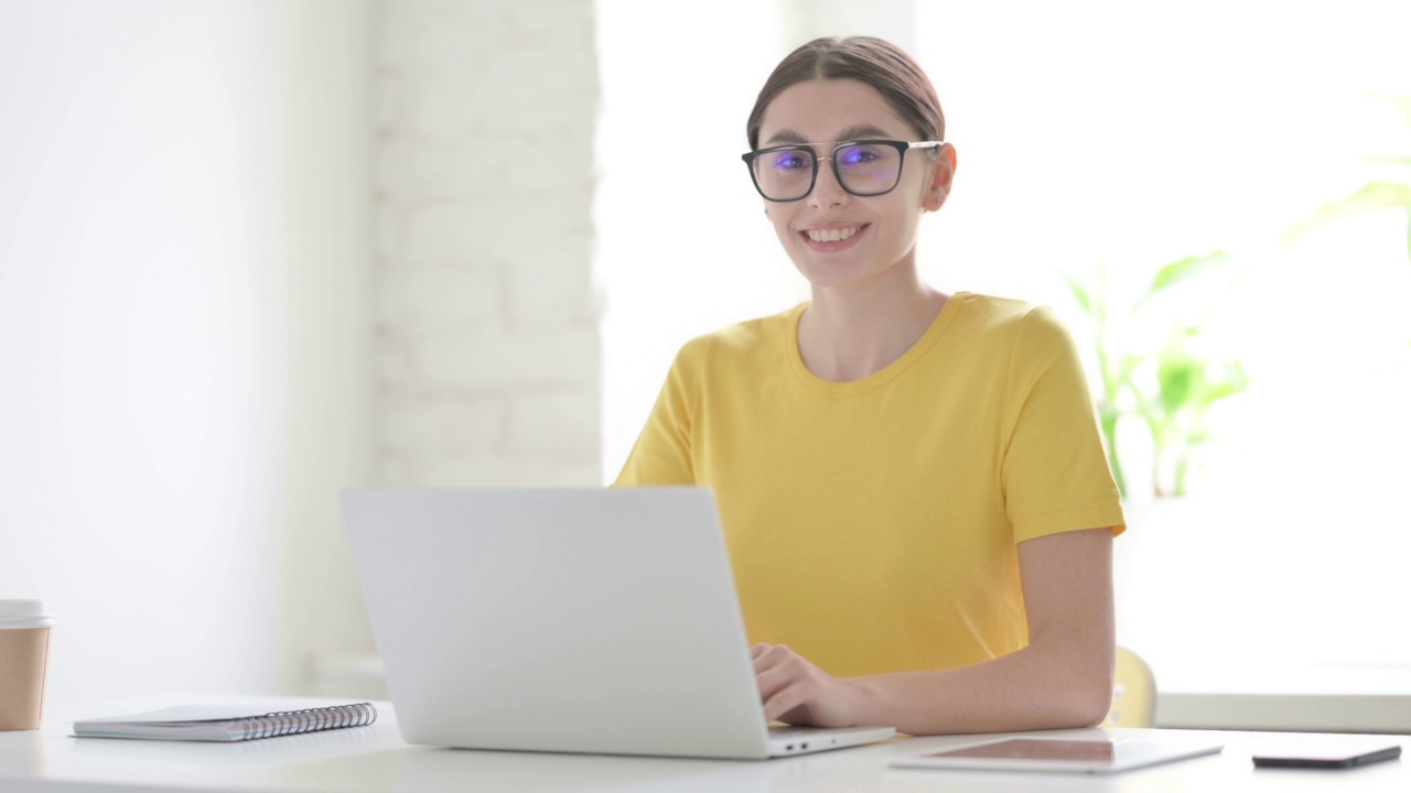 女性在办公室使用笔记本电脑时对着相机微笑视频素材