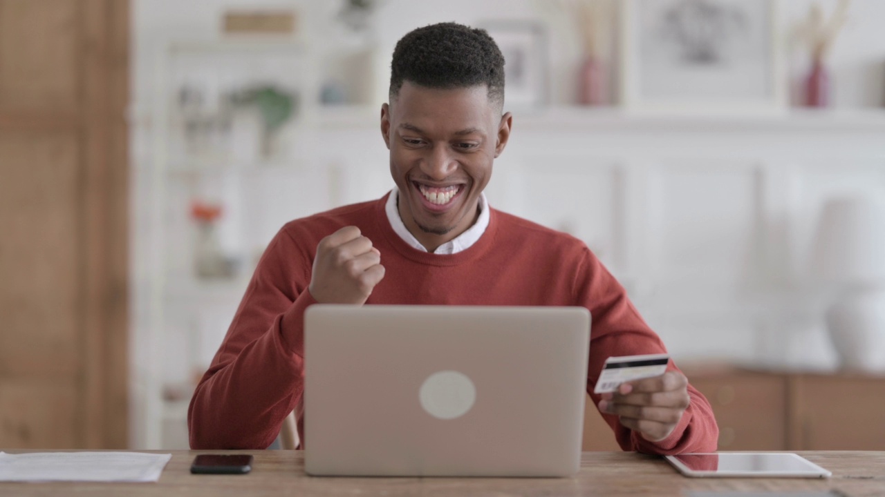 一名非洲男子在笔记本电脑上成功进行在线支付视频素材