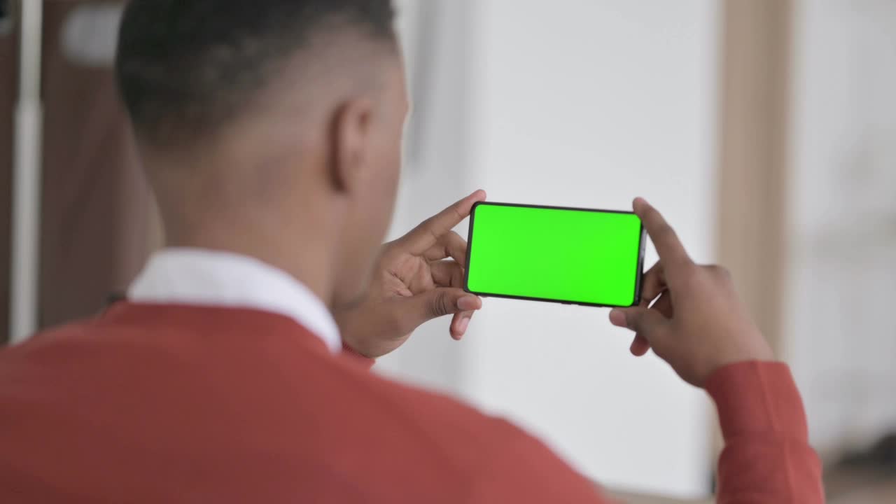 非洲人手持绿色屏幕智能手机的后视图视频素材