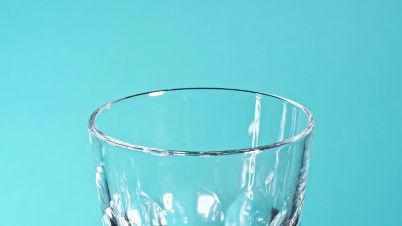 水流落入一个透明的玻璃杯子在慢动作视频素材