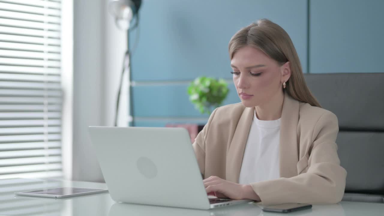 商务女性在办公室使用笔记本电脑时看着相机视频素材