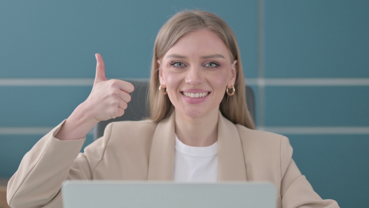 女商人在办公室使用笔记本电脑时竖起大拇指的特写视频素材